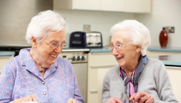 Two senior ladies in kitchen having lunch